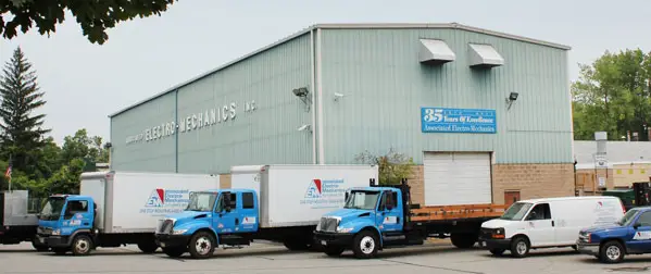 Delivery trucks parked in front of the Associated Electro-Mechanics warehouse.
